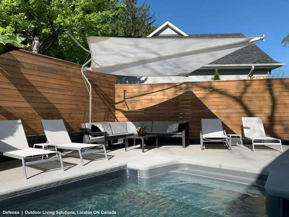 Retractable shade sail over a backyard pool deck
